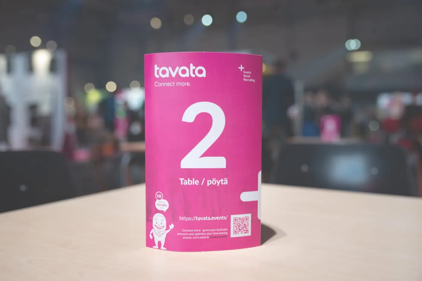 A Tavata table card numbered 2 on a table in a busy event hall