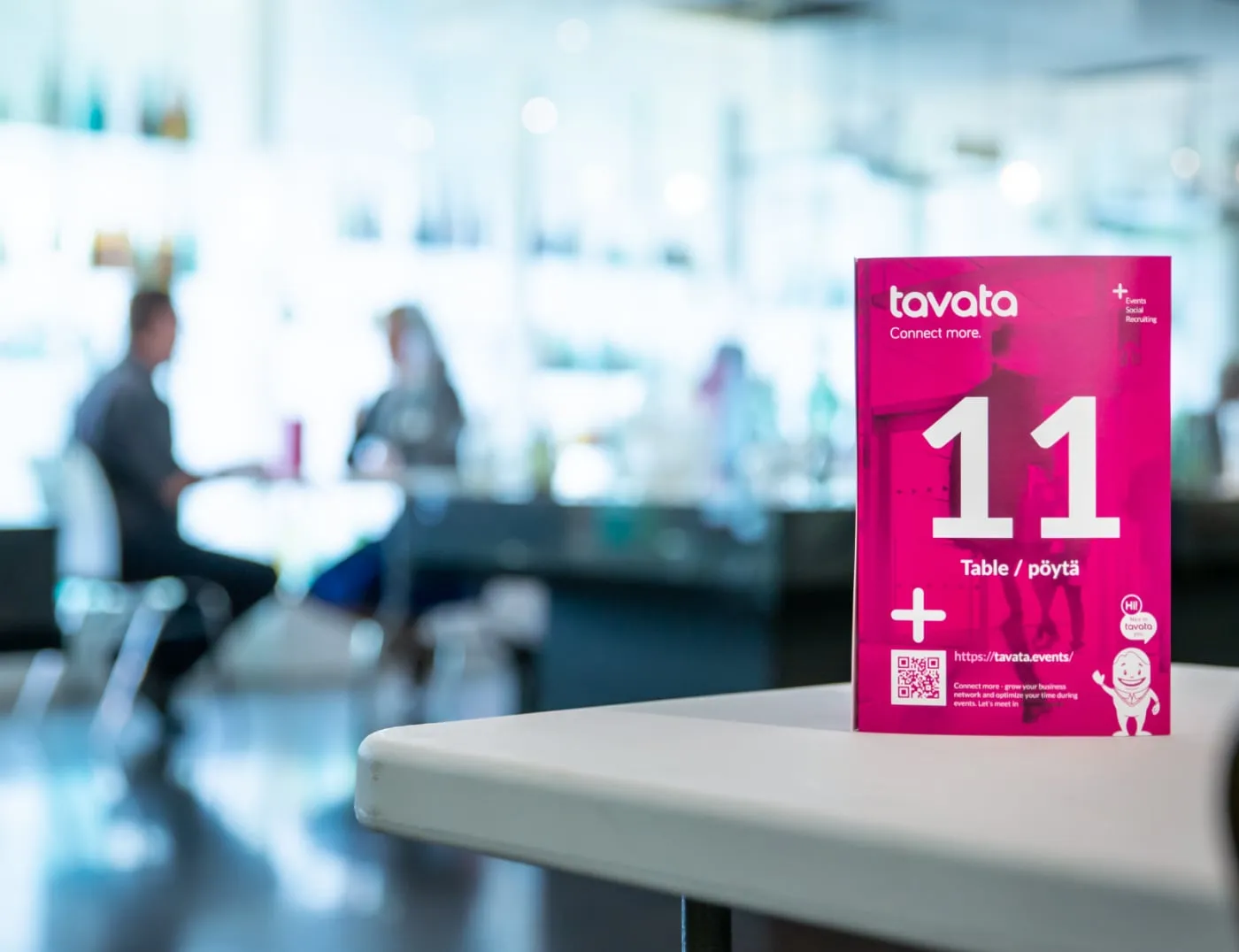 A Tavata table card numbered 11 on a table with attendees meeting in the background