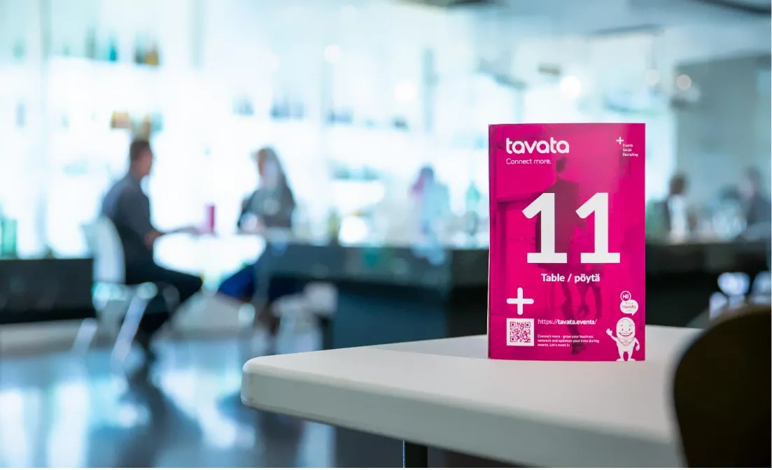 A Tavata table card numbered 11 on a table in a bright venue where people are meeting