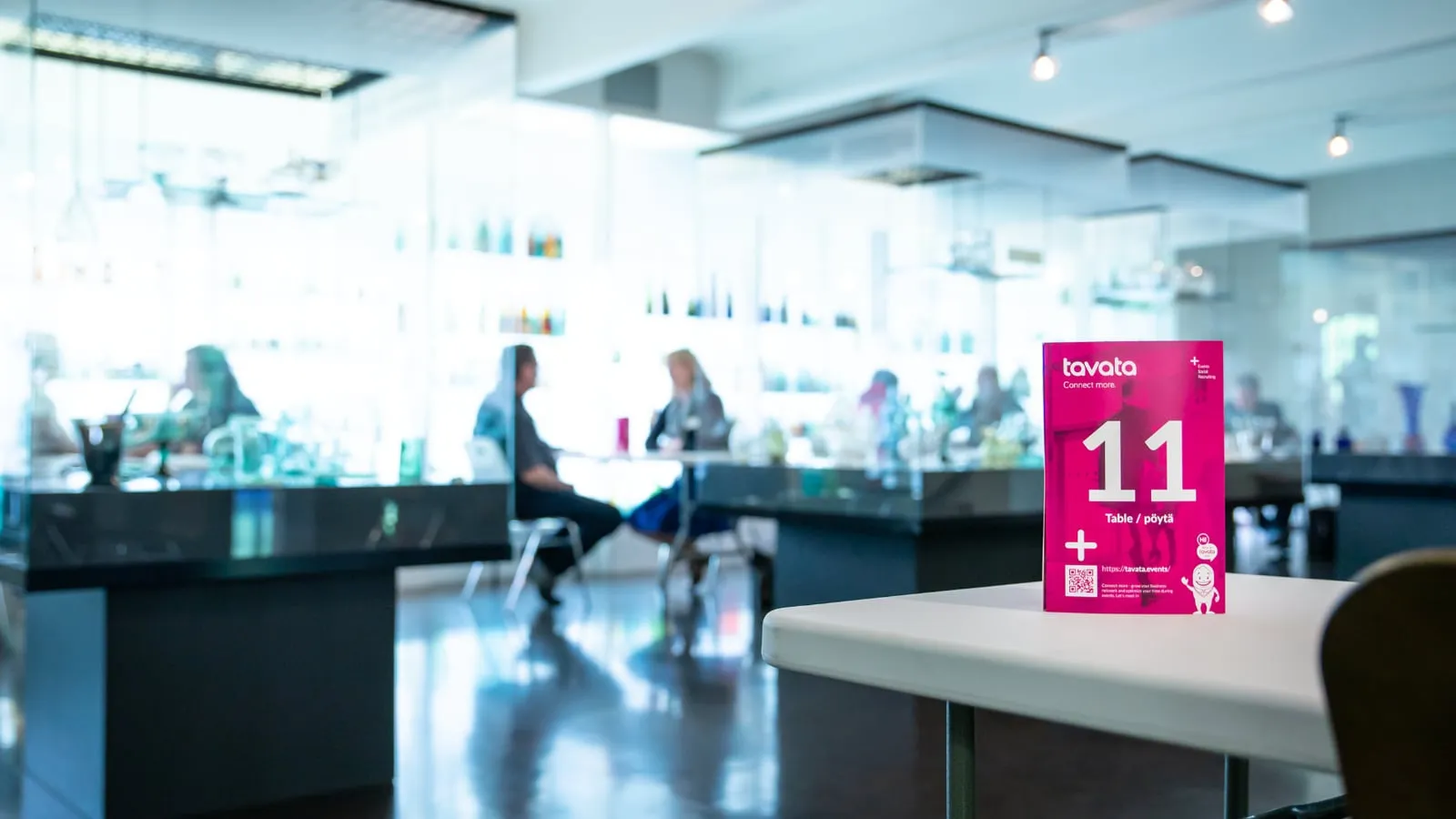 A Tavata table card numbered 11 on a table in a venue where members are meeting
