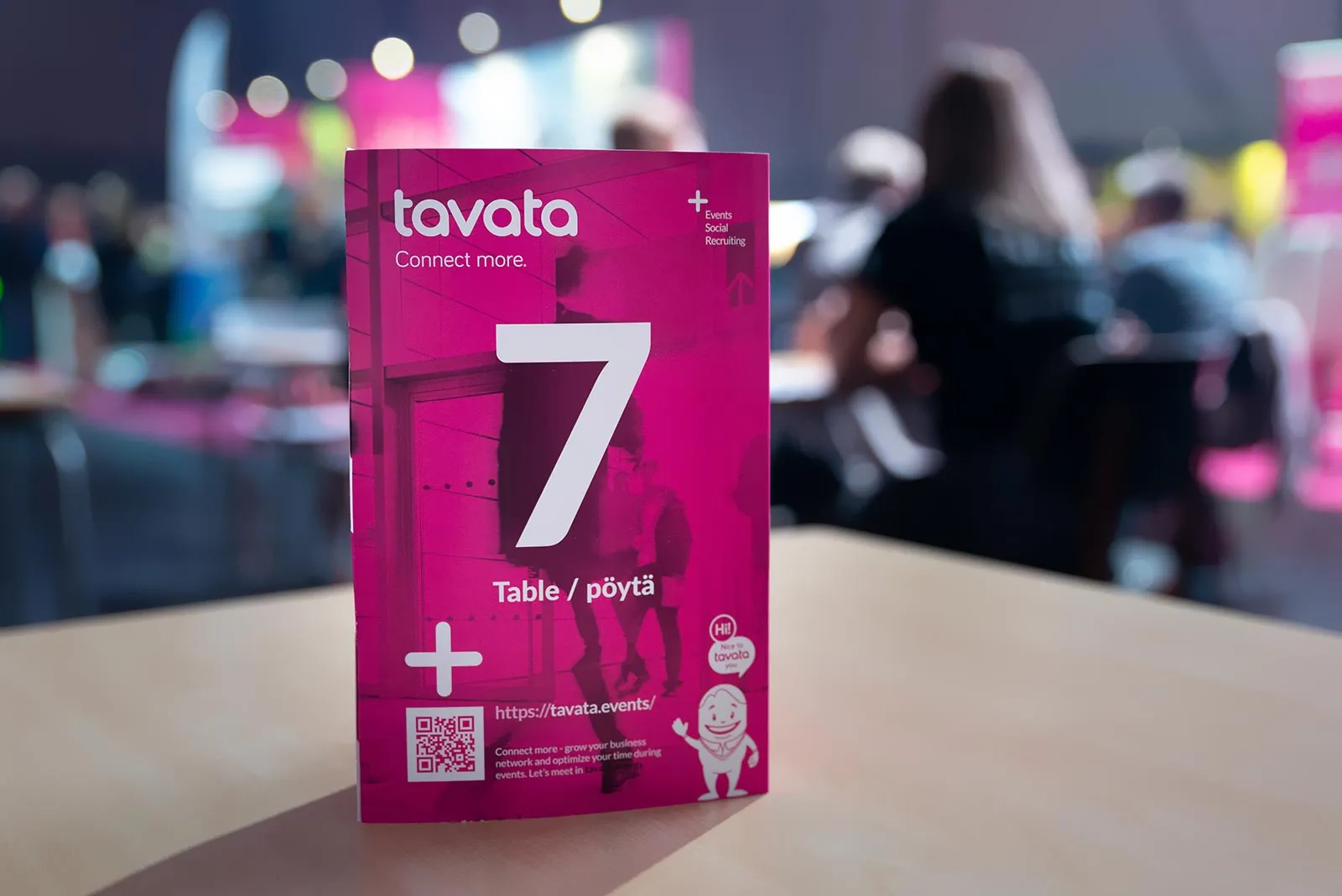 Eine Tavata-Tischkarte mit der Nummer 7 auf einem Tisch in einer belebten Veranstaltungshalle