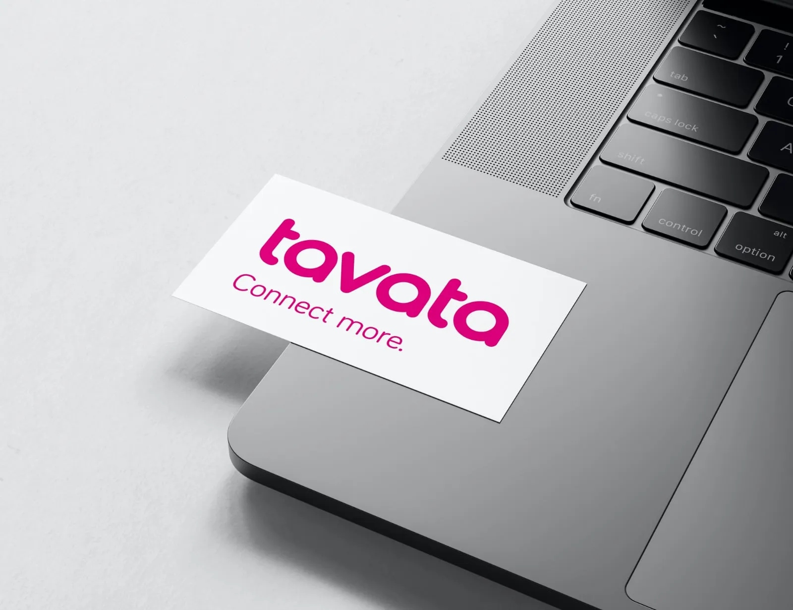 A Tavata business card resting on a laptop keyboard