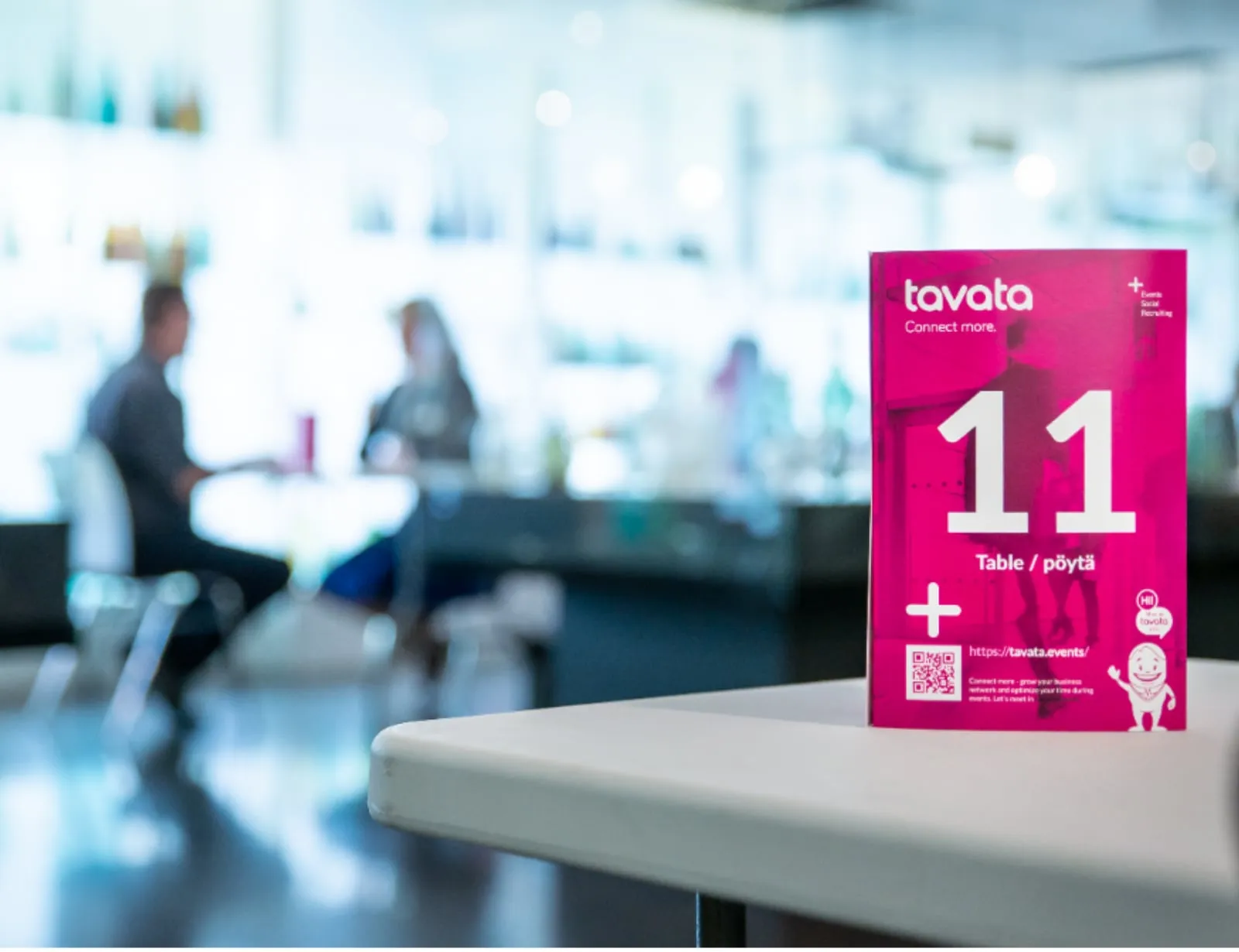 A Tavata table card numbered 11 on a table with attendees meeting in the background